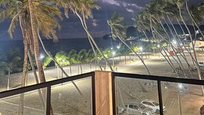 Vista nocturna de una playa con palmeras y una zona arenosa.