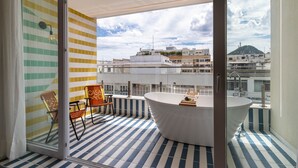 A balcony with a white bathtub, striped floor tiles, and a city view. - Sea View and Balcony with Bathtub | Q5 (Rio de Janeiro)
