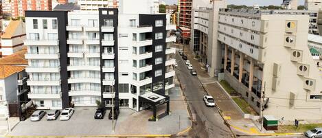 A multi-story hotel with balconies, a parking lot, and a street view.