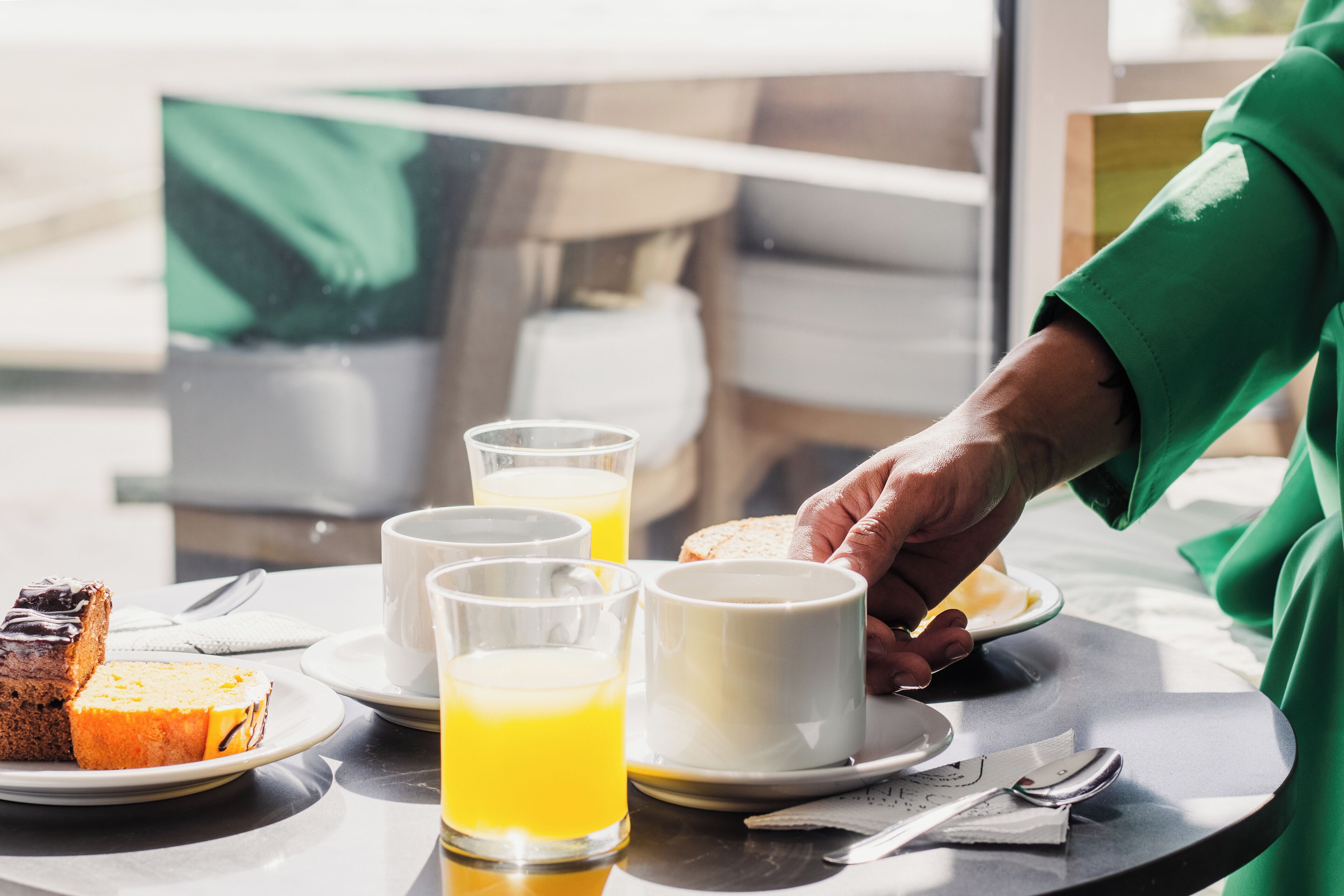 Una mesa de desayuno con una rebanada de pastel, dos vasos de jugo de naranja y un plato de tostadas.
