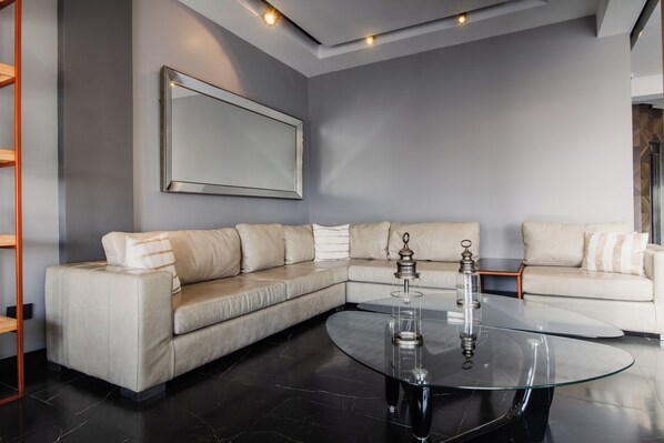 Una sala de estar moderna con un sofá modular, una mesa de centro de vidrio y un espejo grande con marco en la pared.
