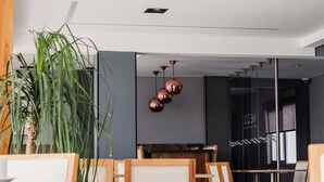 A modern interior with a dining area, a large plant, and a glass partition.