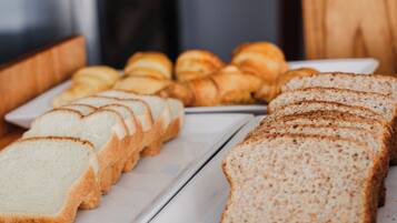 A variety of bread and pastries on a white tray.