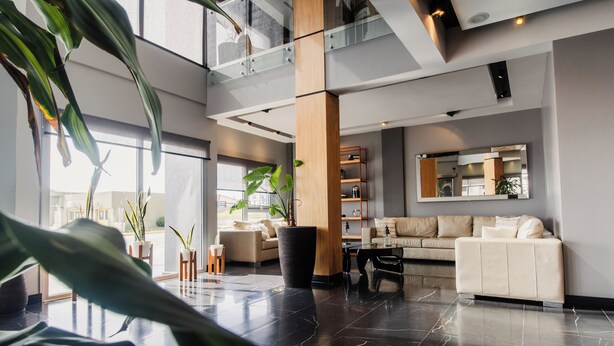 A spacious lobby with a high ceiling, a large black vase, and a beige sofa.