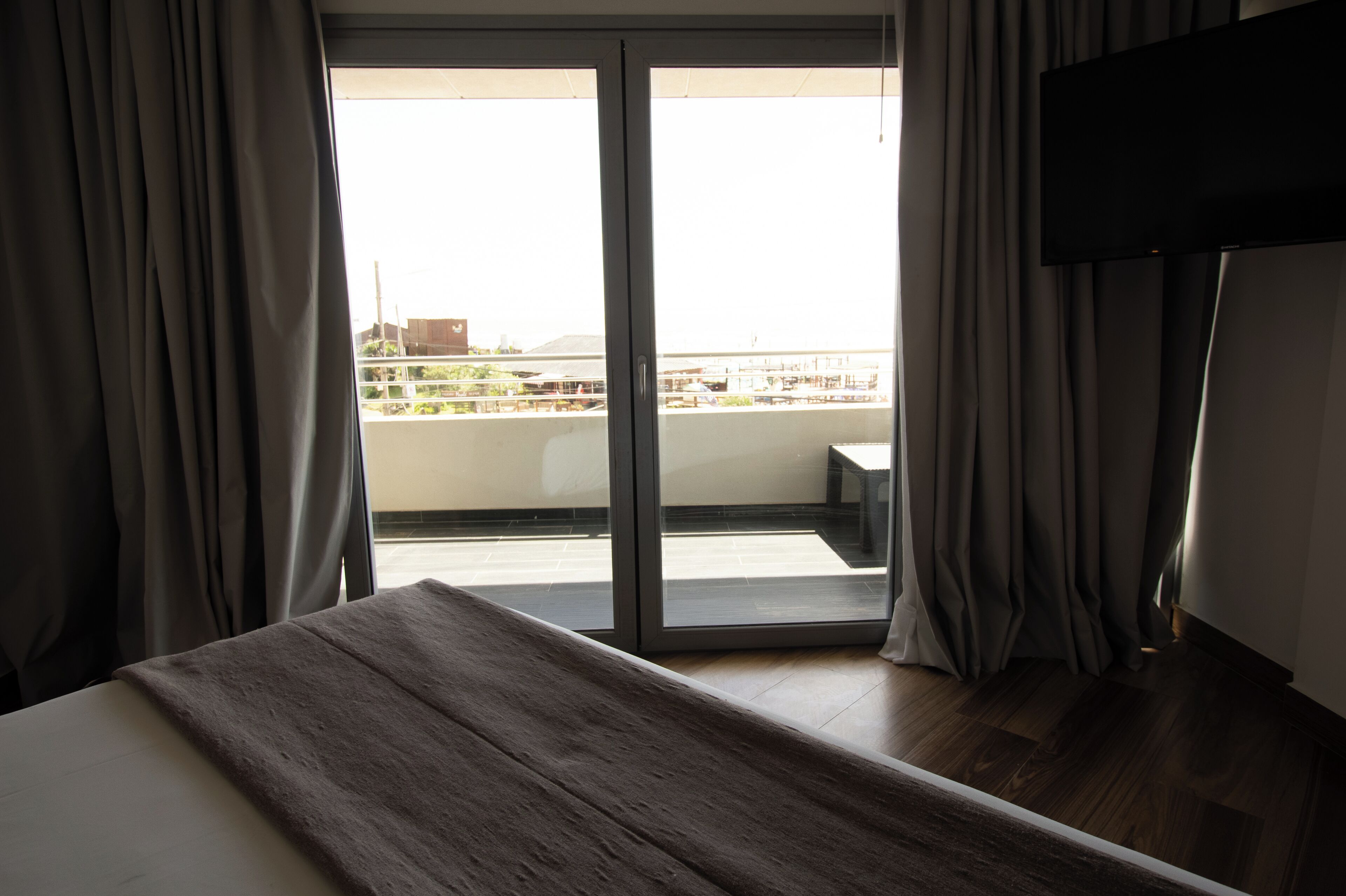 Una habitación de hotel con cama, televisión y balcón con cortinas.
