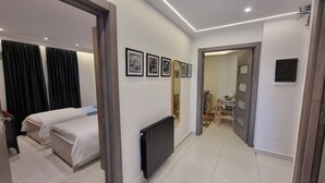 A hotel room with two beds, a radiator, framed pictures on the wall, and a dining area with chairs and a table. - Modern & Restful, Akid Lotfi Oran  (Oran)