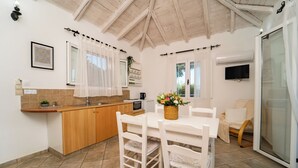 A kitchen with a dining table, chairs, a TV, and a sliding glass door. - vigla vilas  (Zakynthos)