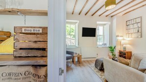 Ett mysigt rum med ett träpanelat tak, en soffa, ett bord och en tv som är monterad på väggen.