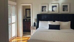 Un dormitorio con una cama grande, un ventilador de techo y cuadros en la pared.