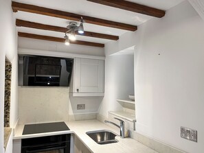 Cozinha com forno embutido, pia e ventoinha no teto.