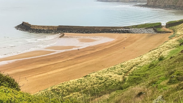 A coastal landscape with a sandy beach, a rocky breakwater, and cliffs. - Hook Cottage - UK48361 (Loftus, near Staithes)