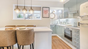 A modern kitchen with a central island, pendant lighting, and a clock on the wall. - Hook Cottage - UK48361 (Loftus, near Staithes)