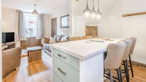 A modern kitchen with a central island, wooden beams, and pendant lighting. - Hook Cottage - UK48361 (Loftus, near Staithes)