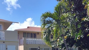 A residential building with a flat roof, a balcony with a lattice design, and a well-maintained lawn. - Condo - 2 beds with WiFi, AC, Pool and Oceanfront in charming Frigate Bay. (Frigate Bay)