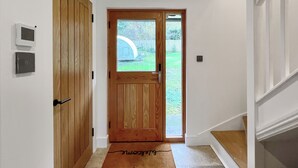 A hallway with a wooden door, a glass door leading outside, and a doormat with the word "Welcome". - 2 bedroom accommodation in Clevedon (Clevedon)