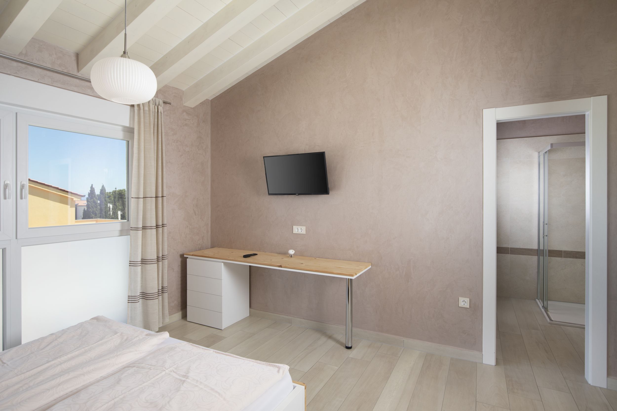 Une chambre comprenant un lit, un bureau, une télévision et un espace douche.
