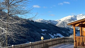 Un gazebo de madera con suelo cubierto de nieve y una valla de madera.