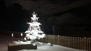 Paisaje nevado con un árbol de Navidad iluminado en el centro.
