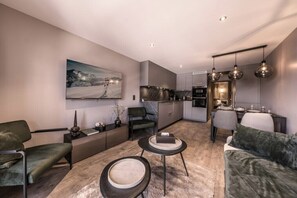 A modern living room with a sofa, a coffee table, and a dining area with a table and chairs.