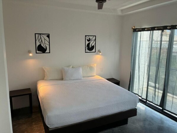 A modern bedroom with a large bed, two wall-mounted light fixtures, and a window with sheer curtains. - Hotel Aria Quinta Avenida & Rooftop Playa del Carmen (Playa del Carmen)