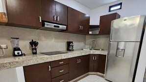 Eine Küche mit dunkelbraunen Schränken, einem Edelstahl-Kühlschrank, einem eingebauten Backofen und einer Arbeitsplatte aus Granit.