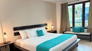 Ein ordentlich eingerichtetes Hotelzimmer mit einem großen Bett, einem Nachttisch, einer Leselampe und einem Fenster mit Vorhängen.