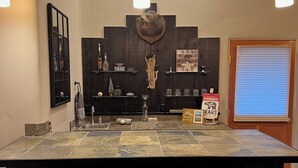 Una cocina con una isla grande, tres taburetes, techo de madera y un reloj montado en la pared.