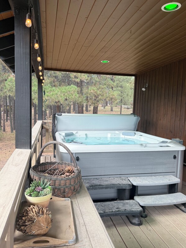 Un jacuzzi con cubierta de madera, una cesta de mimbre y una planta en maceta.