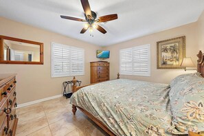 Ein Schlafzimmer mit Bett, Kommode, Deckenventilator und einem Gemälde an der Wand.