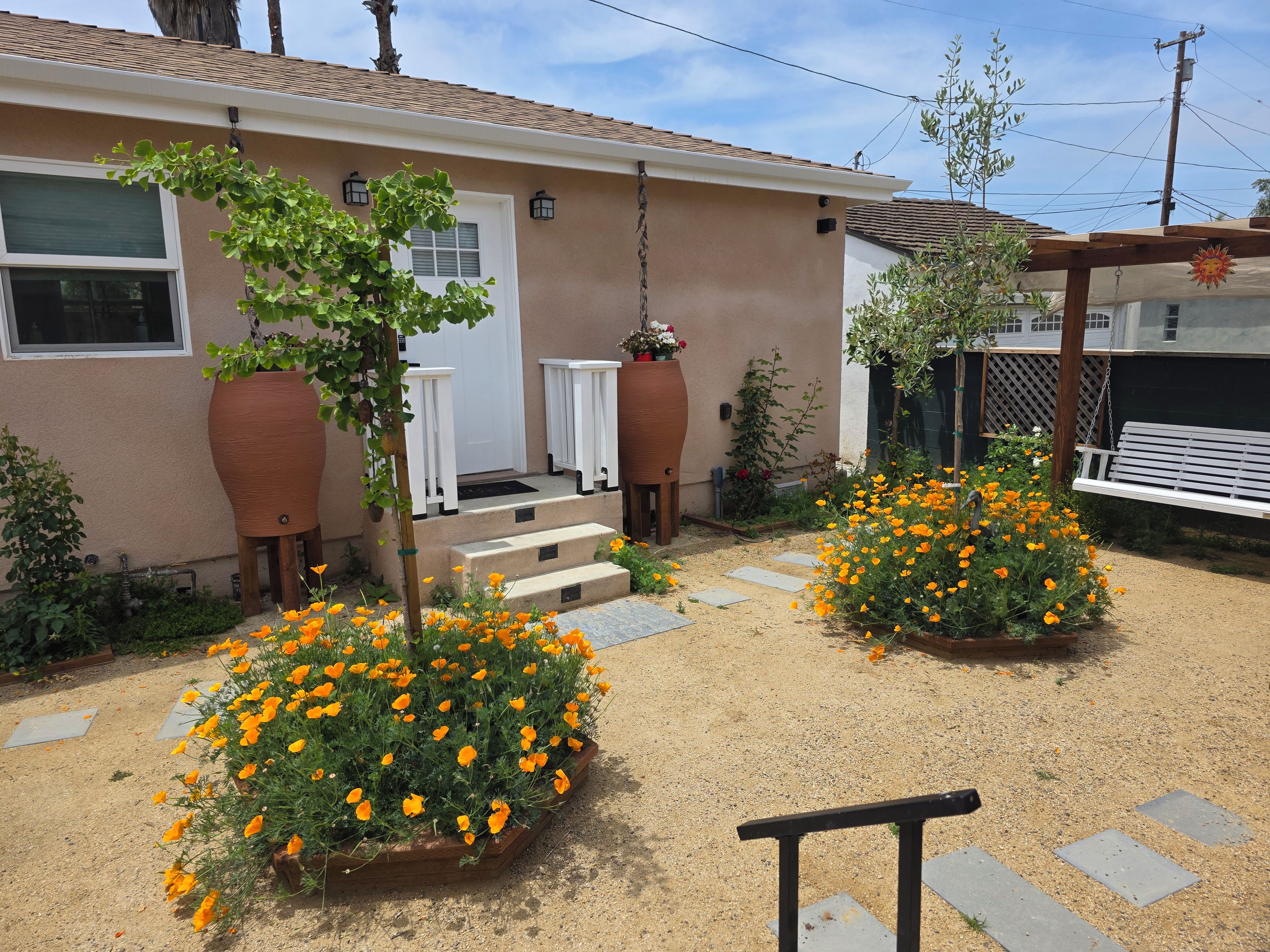 Una propiedad residencial con un porche delantero, una mecedora de madera y un jardín con flores de naranja.