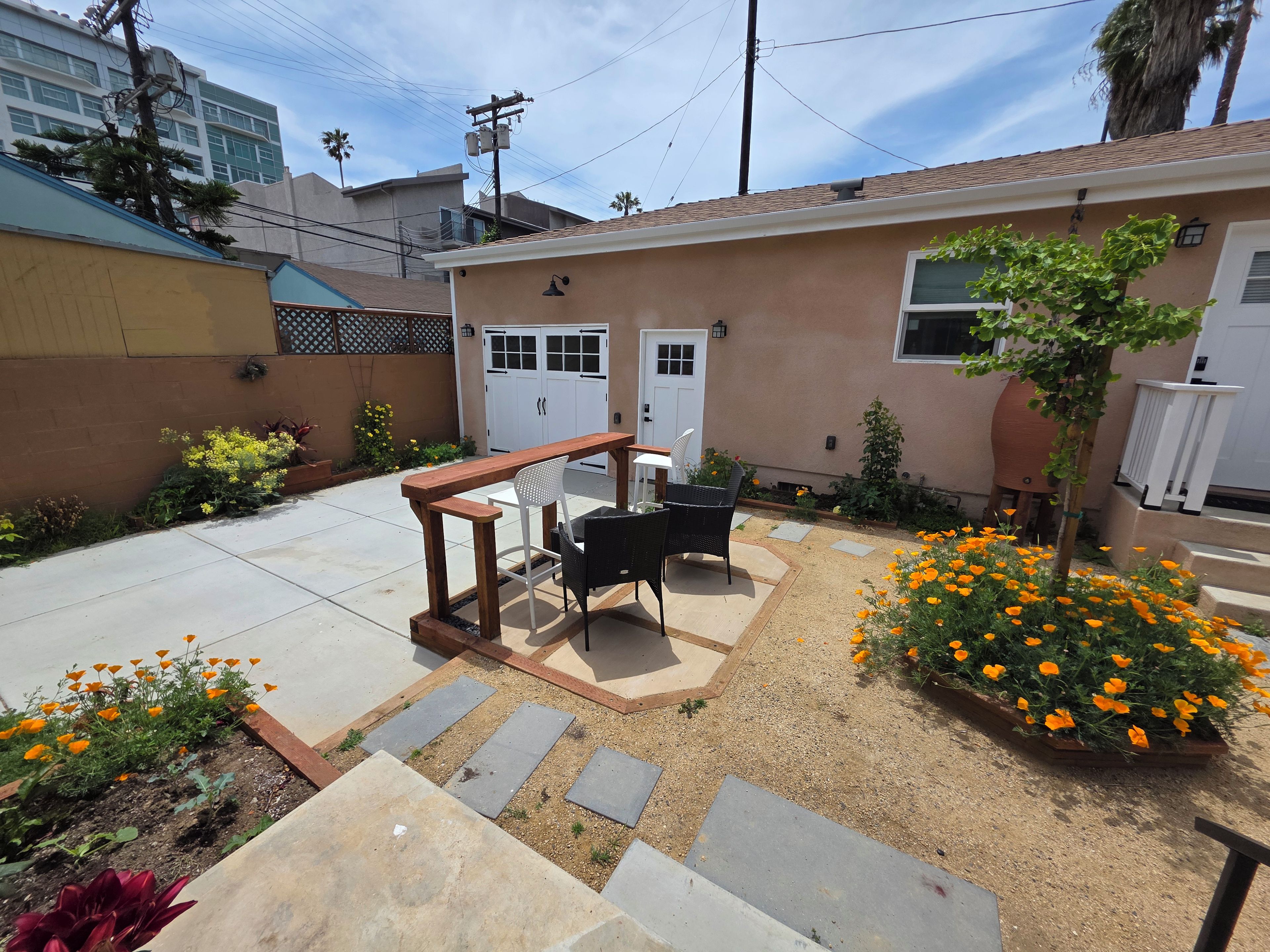 Un patio trasero residencial con mobiliario exterior y plantas florecientes.