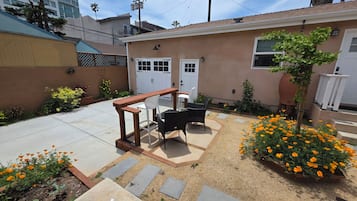 Un patio trasero residencial con mobiliario exterior y plantas florecientes.