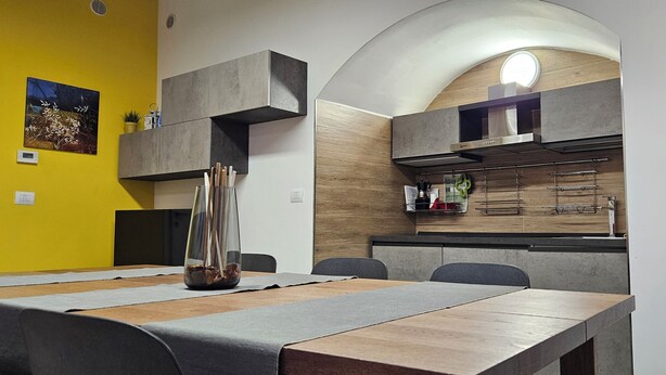 Une cuisine moderne dotée d’un four encastré et d’un coin repas avec une longue table et des chaises.