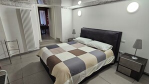 Une chambre à coucher avec un lit, des tables de chevet et une porte donnant sur une autre pièce.