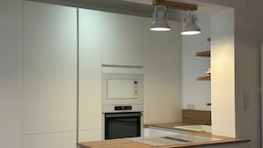 A modern kitchen with white cabinetry, a built-in oven, and a wooden countertop.