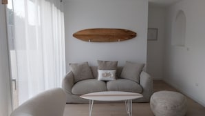 A modern living room with a grey sofa, a round coffee table, and a wooden wall art piece.