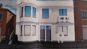 A modern two-story building with a flat roof, large windows, and a small balcony on the upper floor.