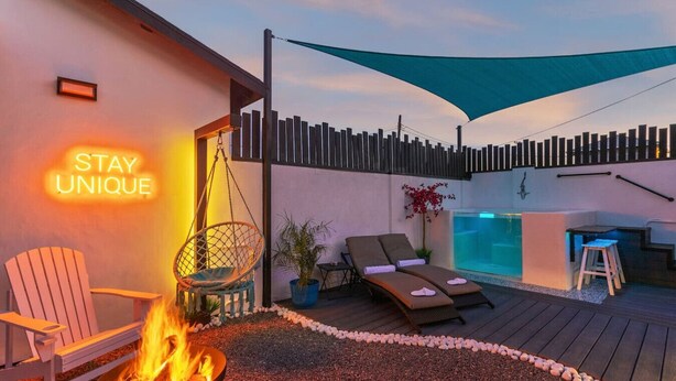 Une agréable terrasse extérieure avec un foyer, des fauteuils confortables et un petit espace piscine.