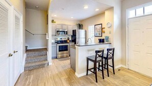 A compact kitchen with a central island, built-in appliances, and a small dining area with stools. - 4 Bedroom 3 Bathroom Villas At Seven Dwarfs 12-108 (Kissimmee)