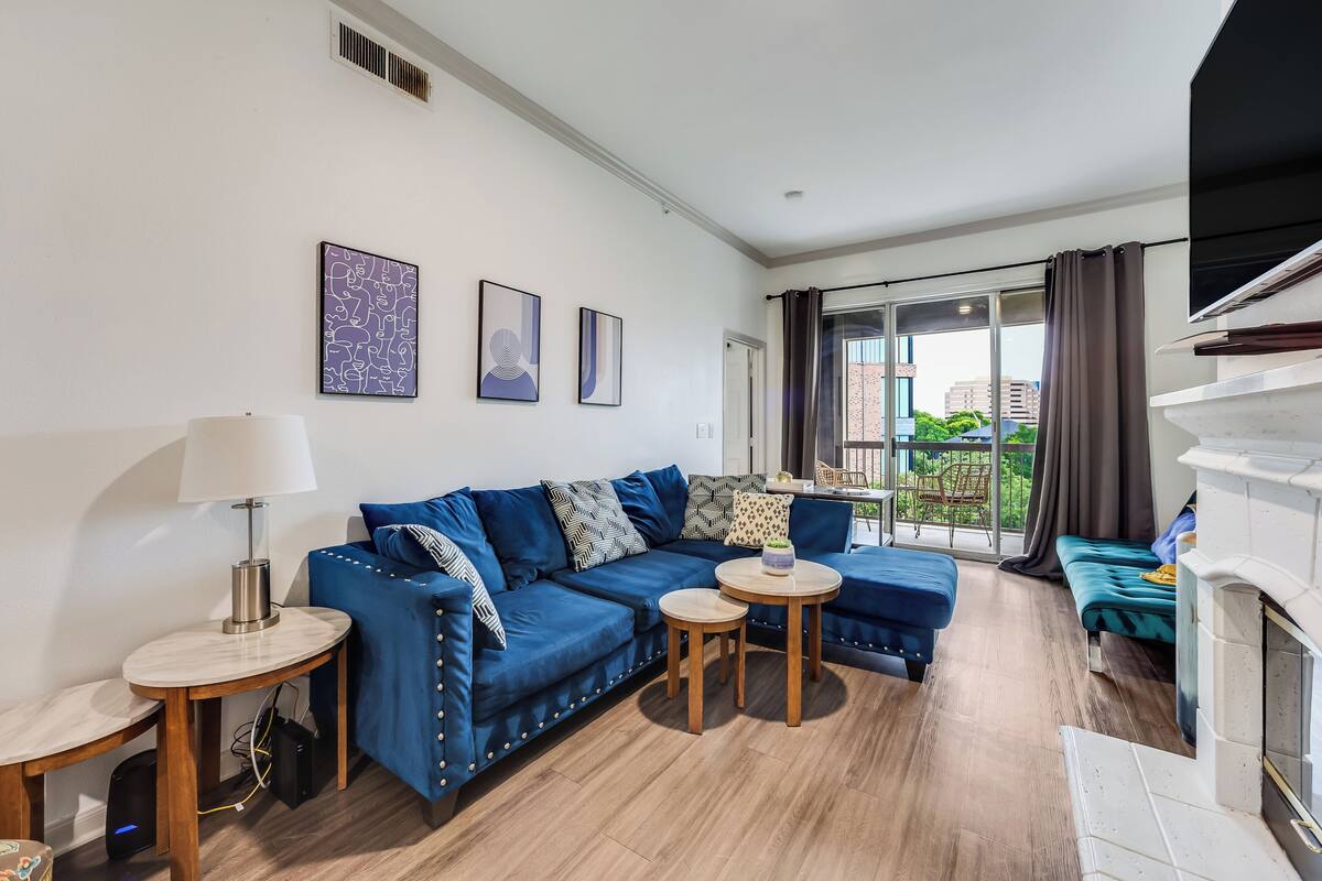 Un salon moderne avec un canapé bleu, une petite table ronde, une lampe et une cheminée.