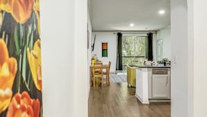 A modern interior with a wooden floor, a kitchen area, and a dining space. - Lynn's Lodging (Austin)