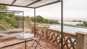 A covered outdoor area with a pool, seating, and a view of the water. - Romantic apartment in idyllic nature setting (Barcelona)