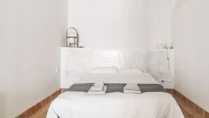 A minimalist bedroom with a bed, a bedside table, and a wall-mounted shelf. - Romantic apartment in idyllic nature setting (Barcelona)
