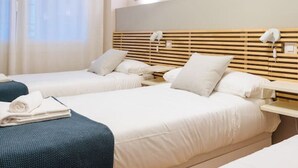Et hotelværelse med to senge, et stort vindue med gardiner og to indrammede abstrakte billeder på væggen.