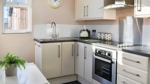 A modern kitchen with a built-in oven, stainless steel appliances, and a window above the sink. - 2 bedroom accommodation in Wilsthorpe (Wilsthorpe)
