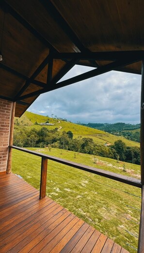 A wooden deck with a view of a hilly landscape. - Chalé eu na montanha  (Santo Antonio do Pinhal)