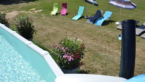 A poolside area with a swimming pool, lounge chairs, and umbrellas.