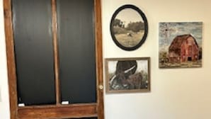 Une pièce avec une grande fenêtre à cadre en bois, une horloge murale et deux tableaux encadrés.