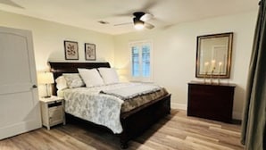 Une chambre à coucher comprenant un lit, une table de chevet, une commode et un ventilateur de plafond.