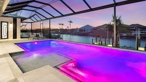 Ein Pool ohne Ende mit Glasdach, Blick auf das Wasser und ein Sonnenuntergang.